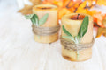 Two pillar candles wrapped in twine with sage