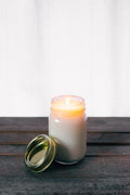 Golden Hour amber soy candle glowing by a window